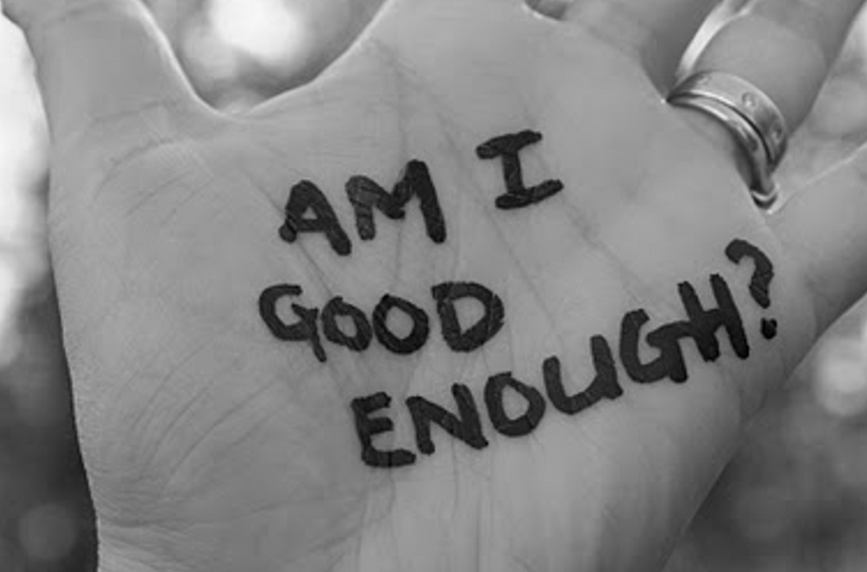 Hand with writing on it saying "Am I good enough?"